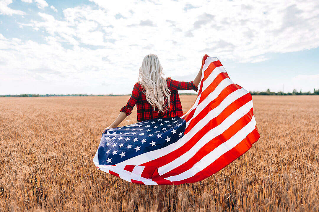 A Woman Walking in a Field with The American Flag