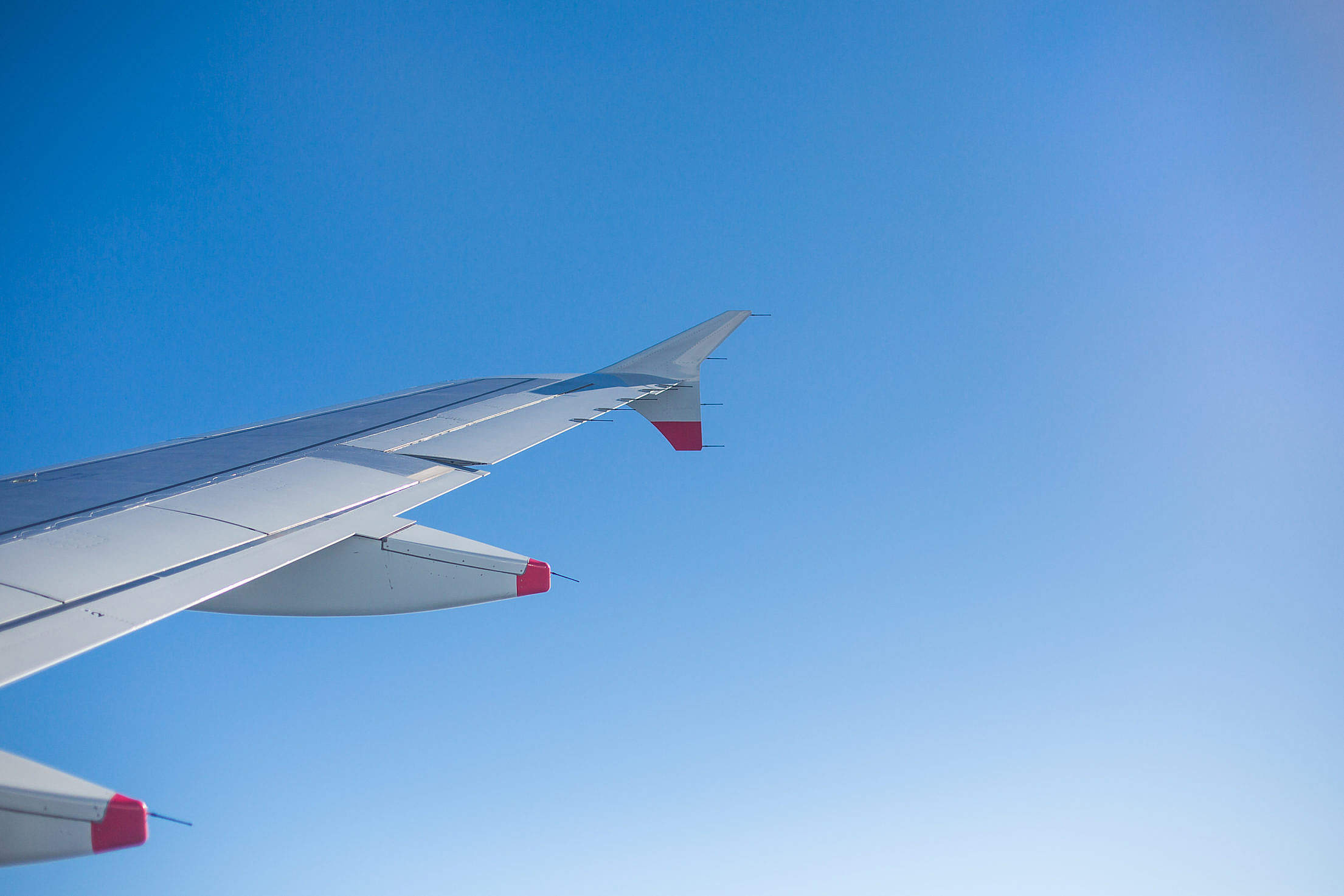 Airplane Wing and Bright Sky Through an Airplane Window Free Stock Photo