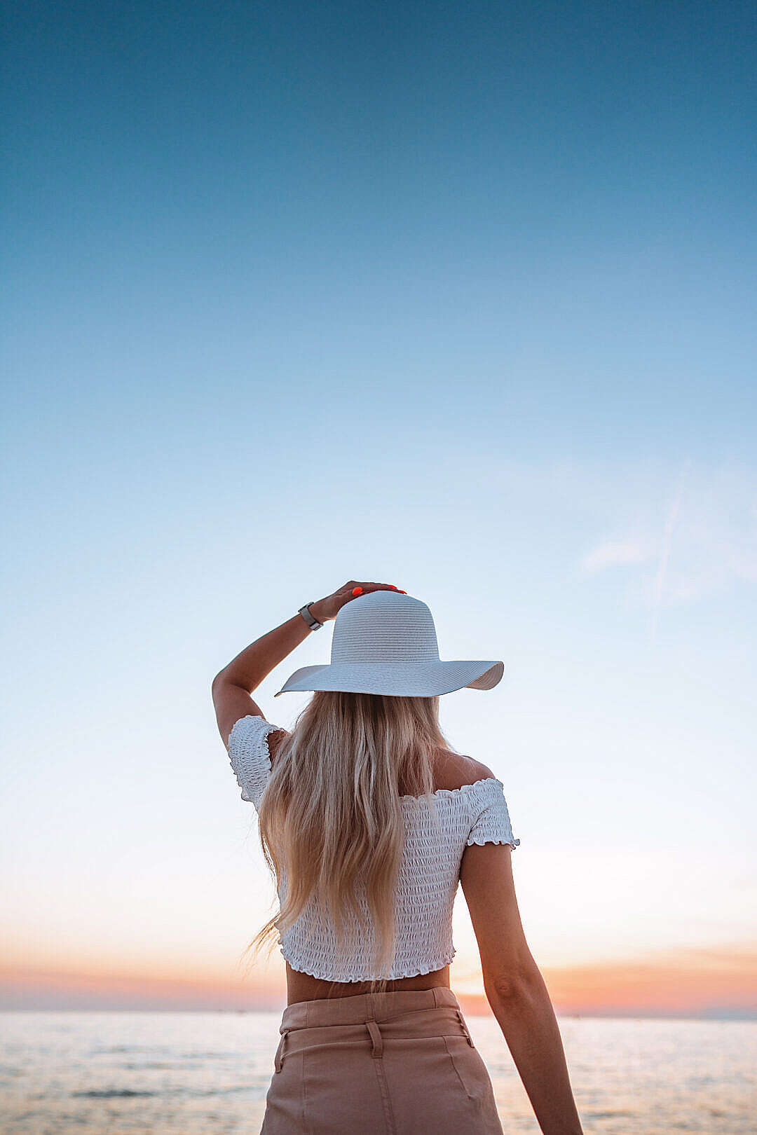 Download Beautiful Woman in a Hat Enjoying Sunset by the Sea FREE Stock Photo