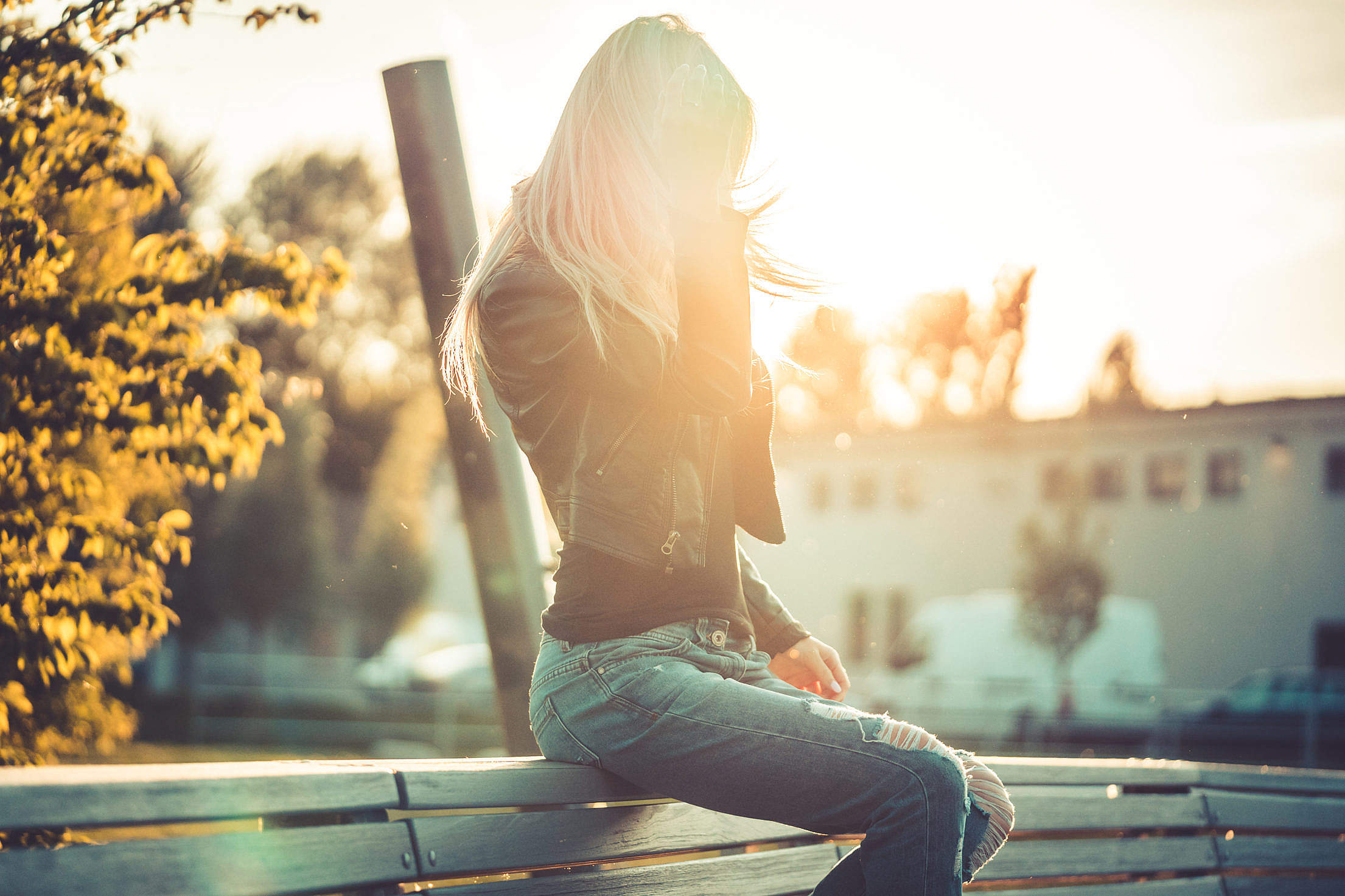 Blonde Woman Sitting Alone on a Bench Against Sunset Free Stock Photo