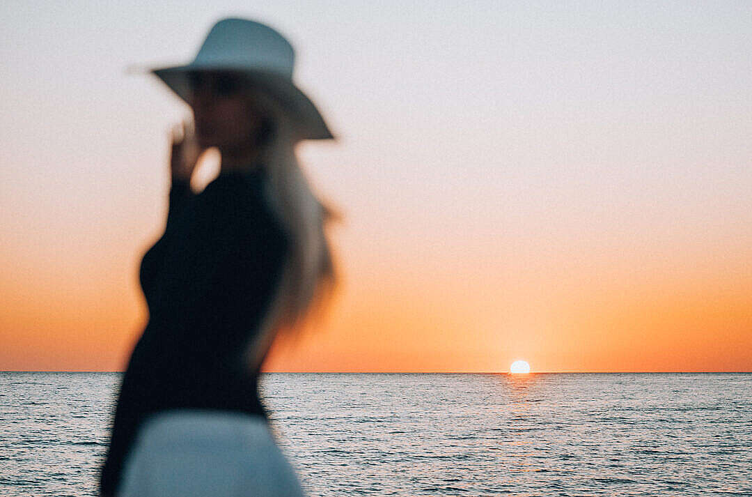 Download Blurred Silhouette of a Woman Enjoying Sunset by The Sea FREE Stock Photo