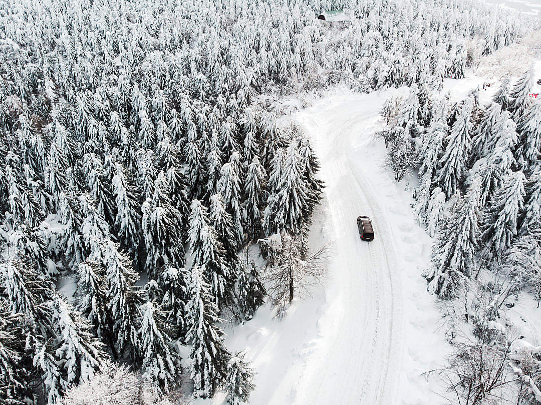 Car Driving on a Snowy Road in The Woods