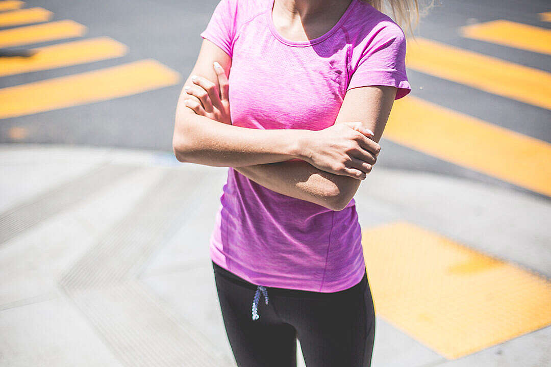 Fitness Girl Waiting At a Street Corner Near The Pedestrian Crossing