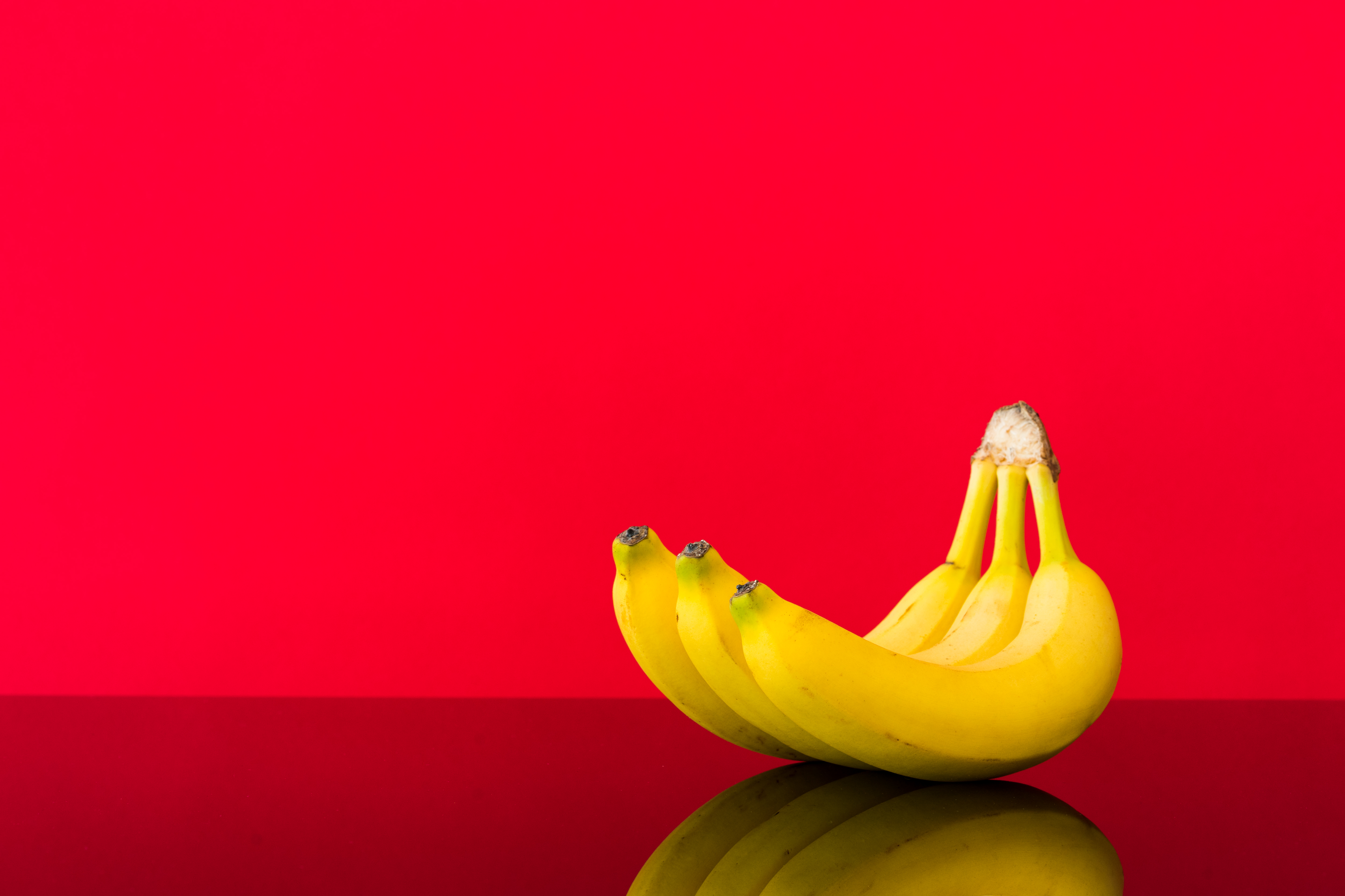 Organic bananas on red background top view. Bunch of bananas is lying on  orange background with dark spots marking ripening process Stock Photo -  Alamy