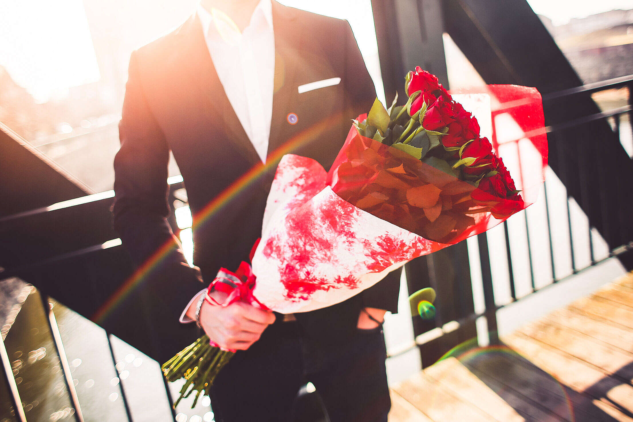 Gentleman Holding a Bouquet of Roses and Waiting for His Wife Free Stock Photo