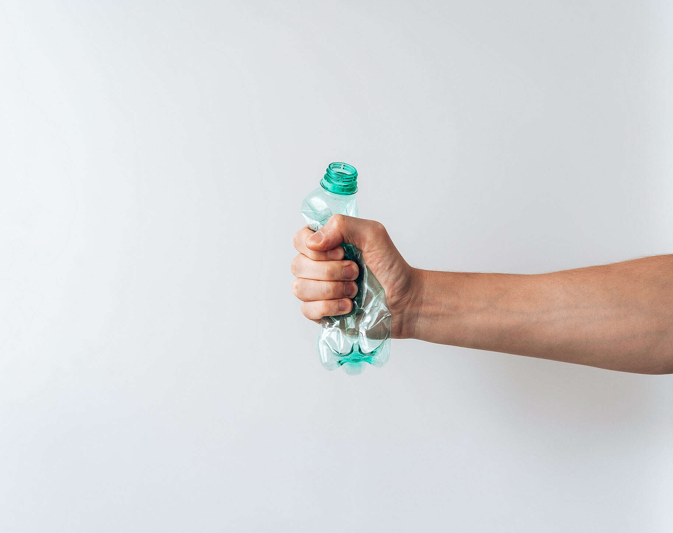 Hand Holding a Crumpled Plastic Bottle Free Stock Photo