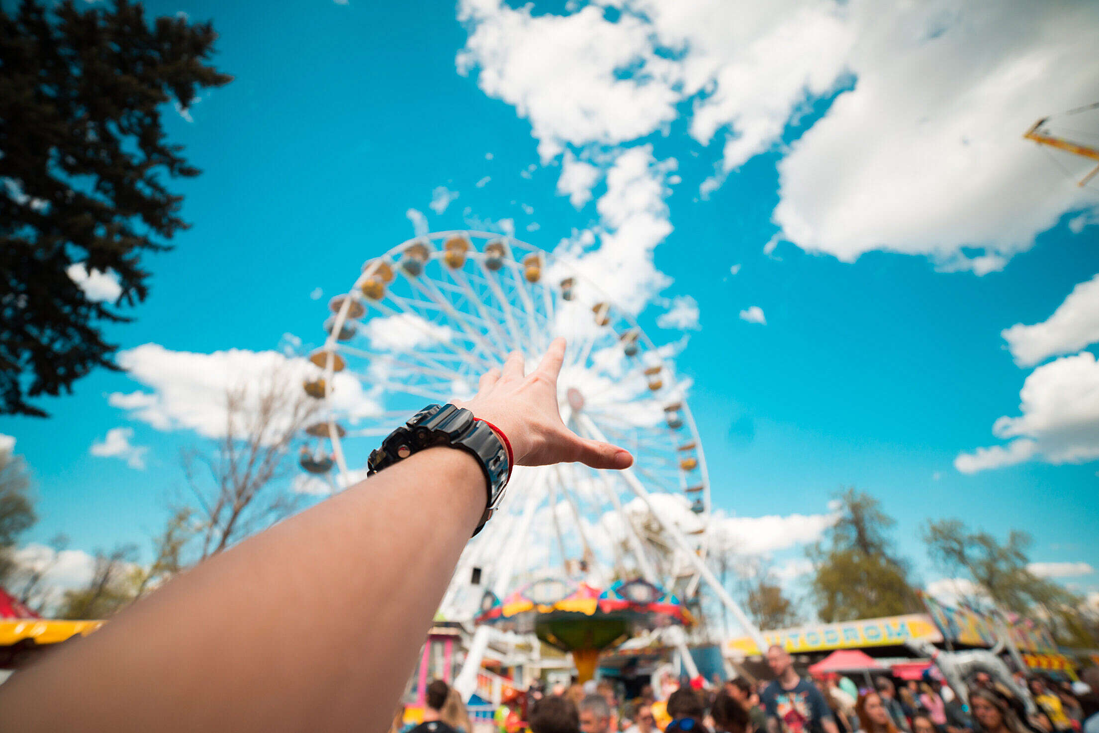 Hand Reaching the Ferris Wheel in Amusement Park Free Stock Photo