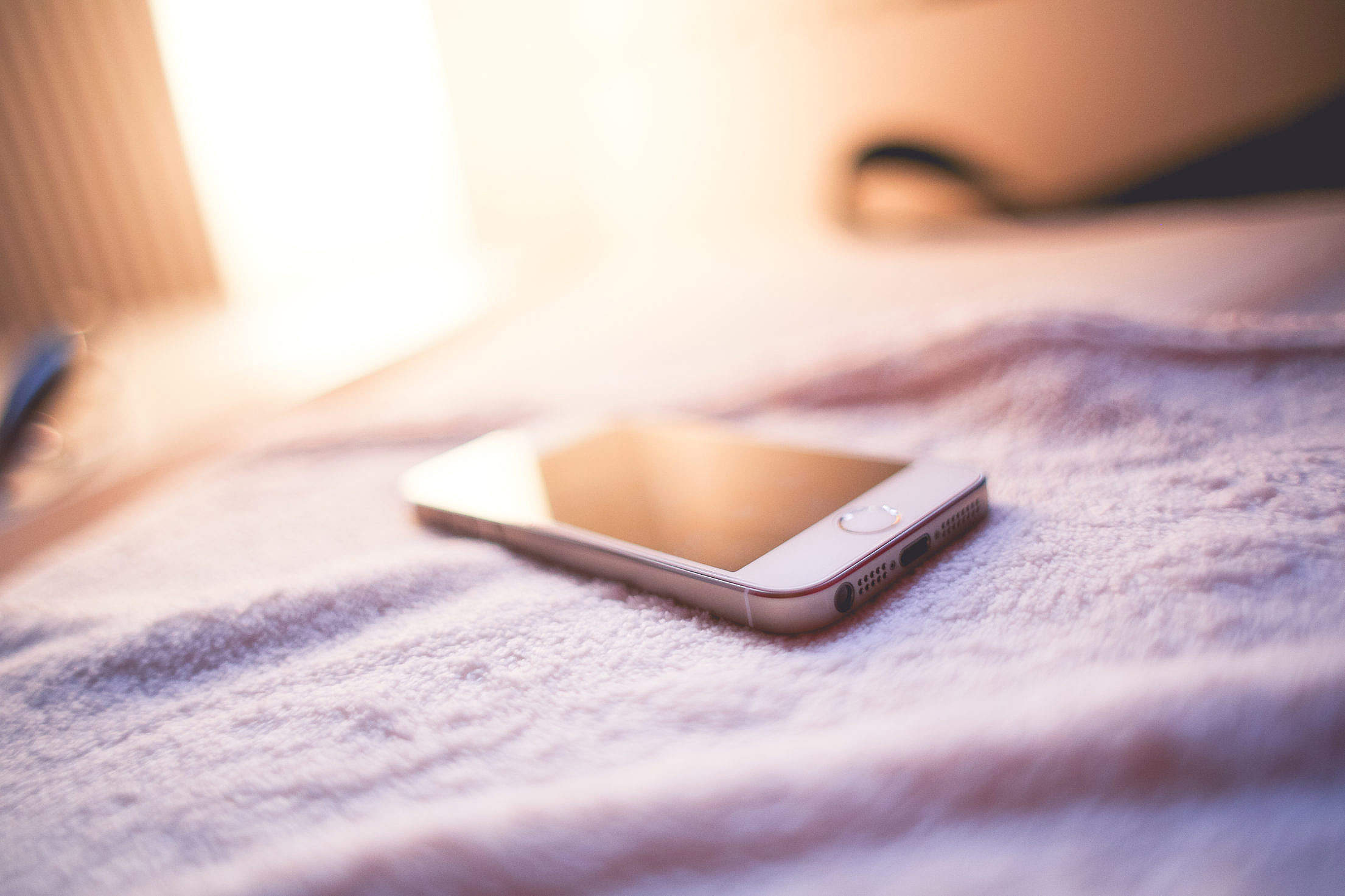 iPhone 5S Gold in a Bed Free Stock Photo