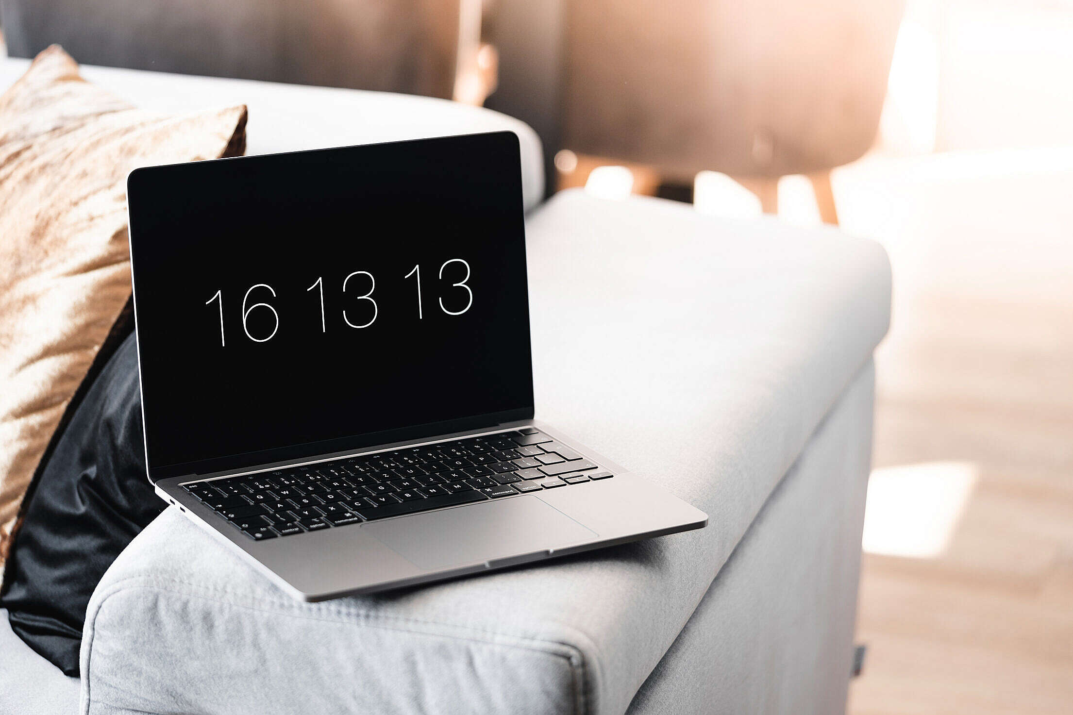 Laptop with a Clock Screensaver on a Sofa Free Stock Photo