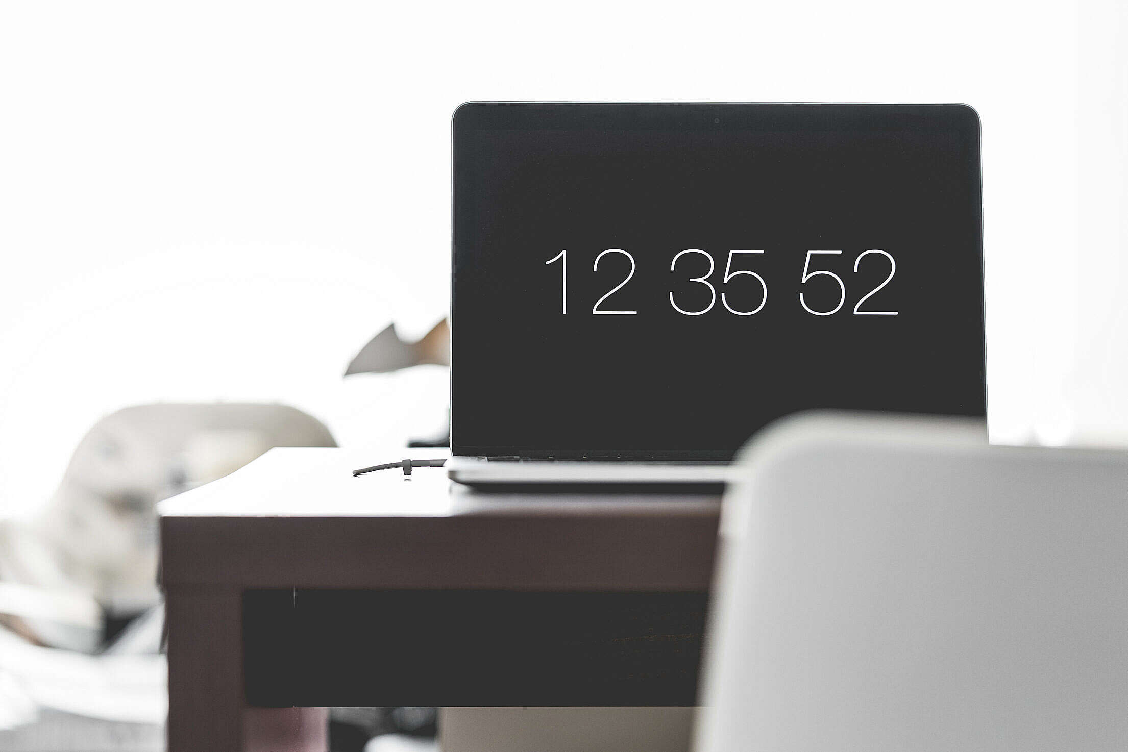 Laptop with Time Screen Saver on Office Desk Free Stock Photo