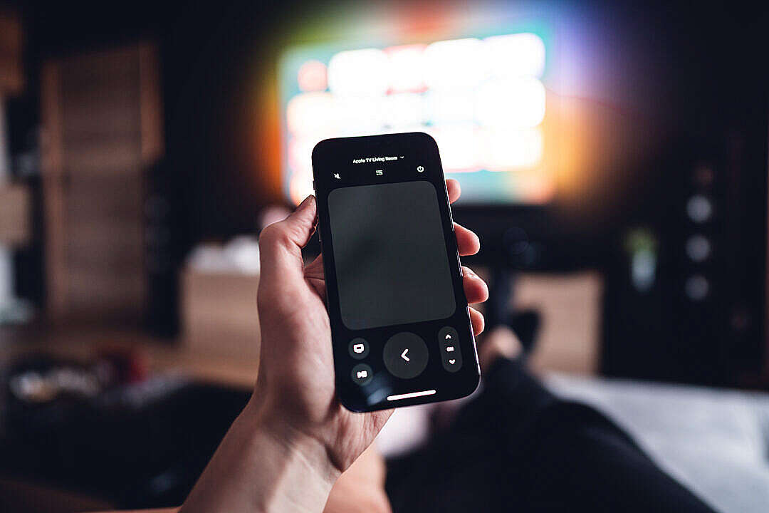 Download Man Controlling Apple TV via iPhone Remote FREE Stock Photo
