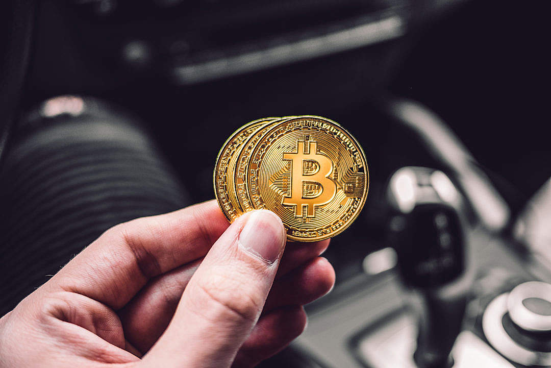 Man Holding a Bitcoin Coin in a Car