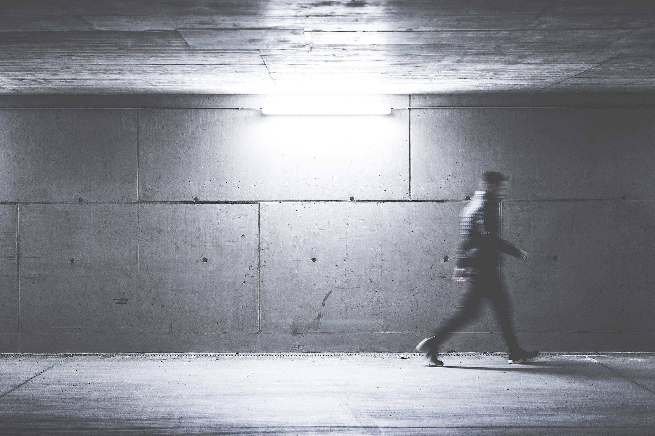 Man Walking Through Concrete Underpass Free Stock Photo