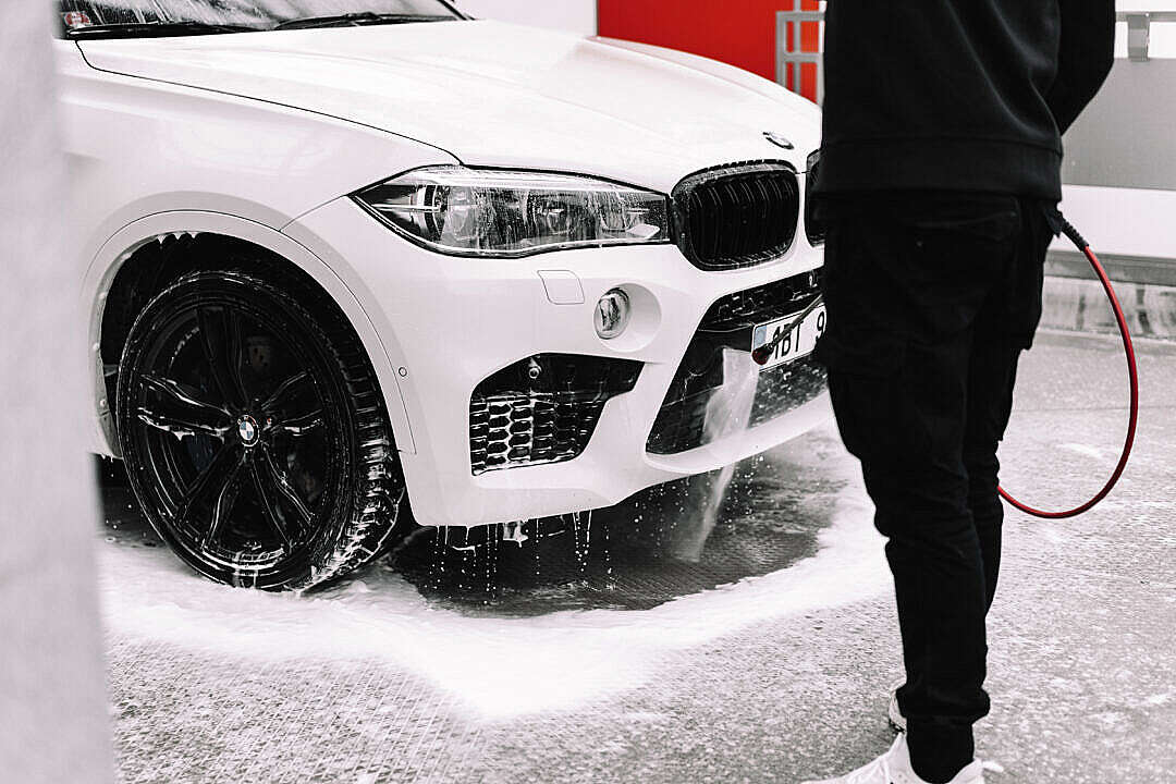 Man Washing White Car in a Self-Service Car Wash