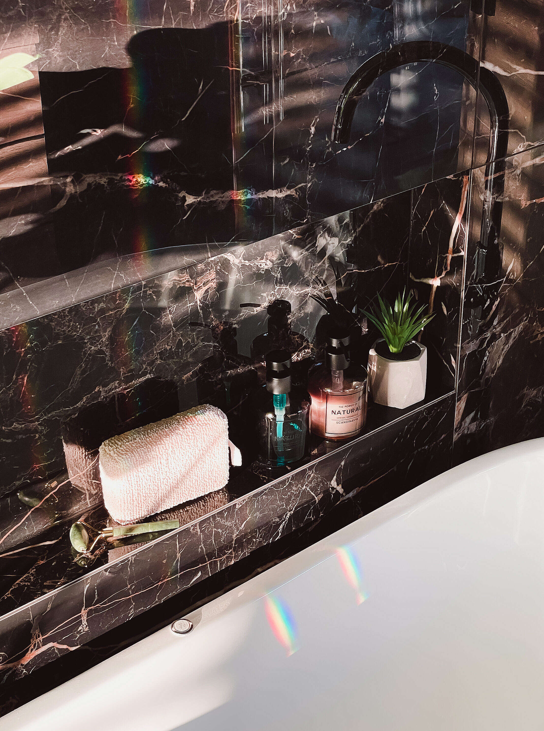 Modern Black Glossy Marble Bathroom Detail with Shampoos and Shower Sponge Free Stock Photo