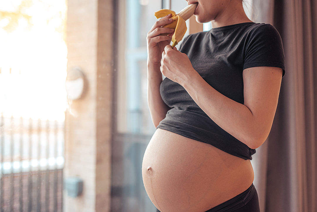 Download Pregnant Woman Eating a Banana After Workout FREE Stock Photo