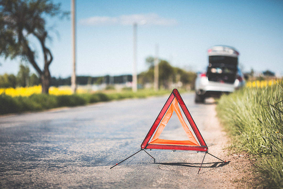 Red Warning Triangle and Broken Car on The Road
