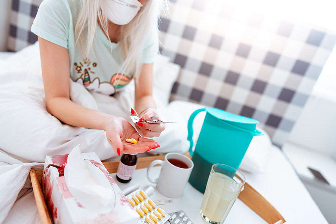 Sick Woman Sitting in a Bed and Taking Medications