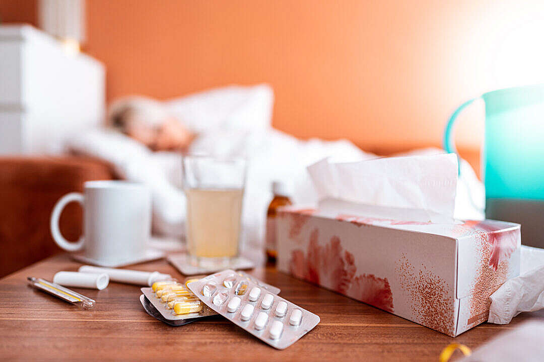 Download Sick Woman Sleeping in a Bed with a Focus to a Pack of Tablets Lying on The Table FREE Stock Photo