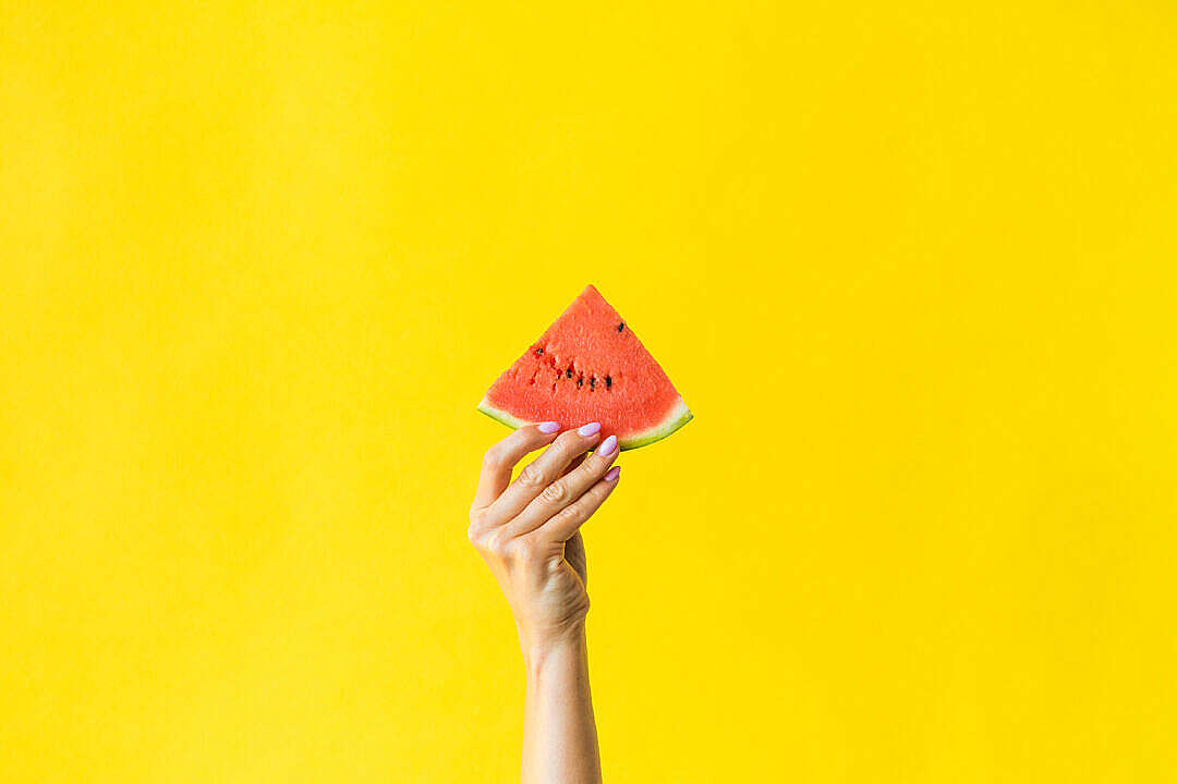 Download Slice of Watermelon in Woman Hand on Bright Yellow Background FREE Stock Photo