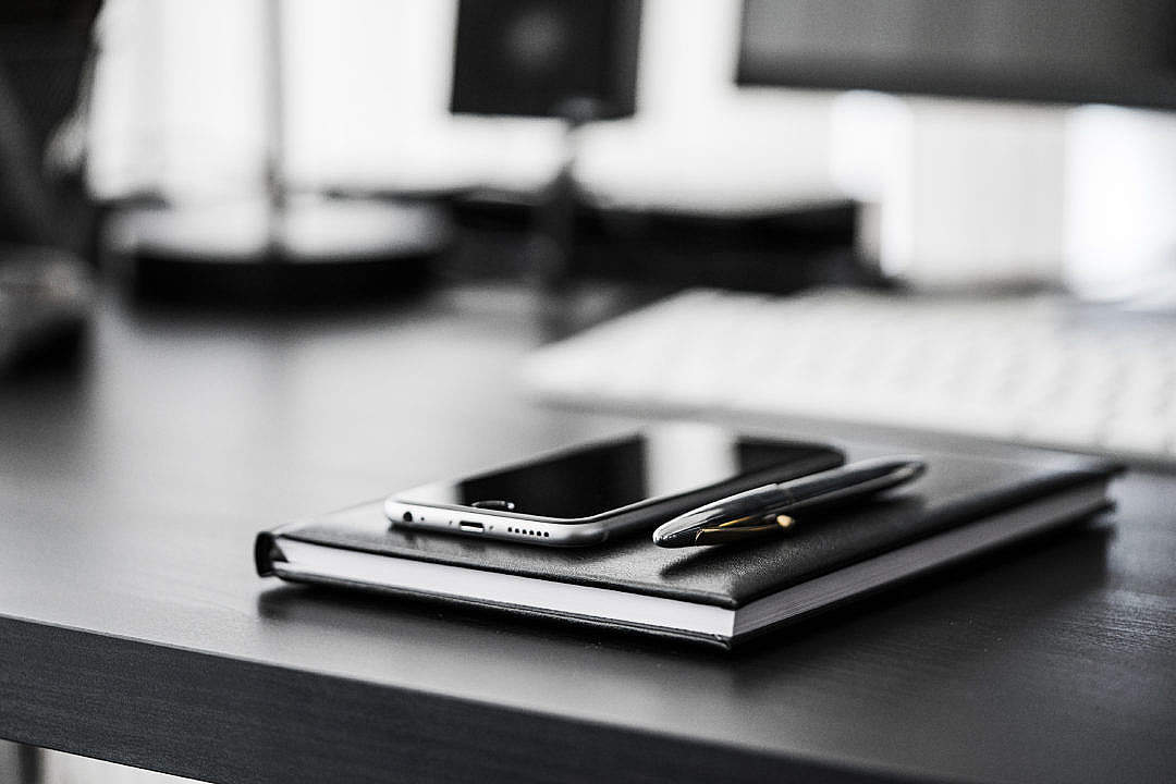 Smartphone, Diary and Silver Pen on Black Workspace Desk