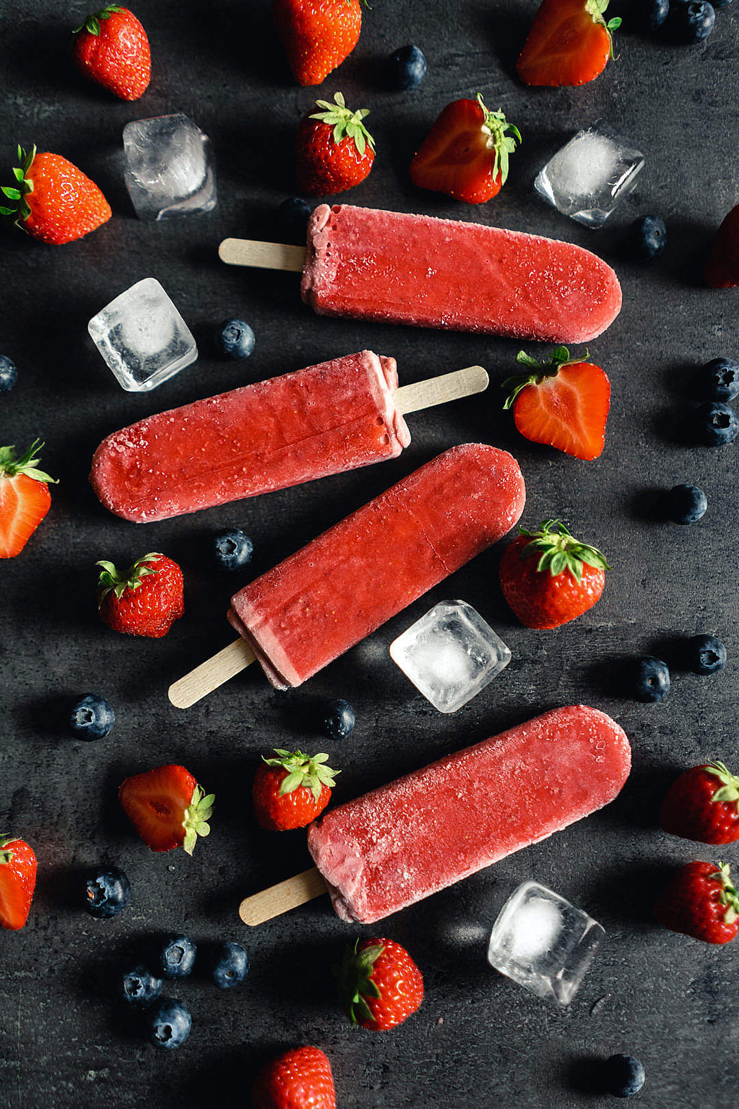 Strawberry Ice Lollies with Fresh Blueberries on Black Background
