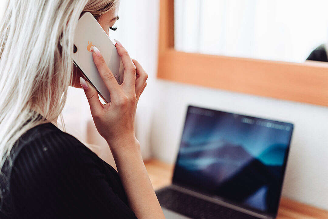 Download Woman Calling While Working on Laptop FREE Stock Photo