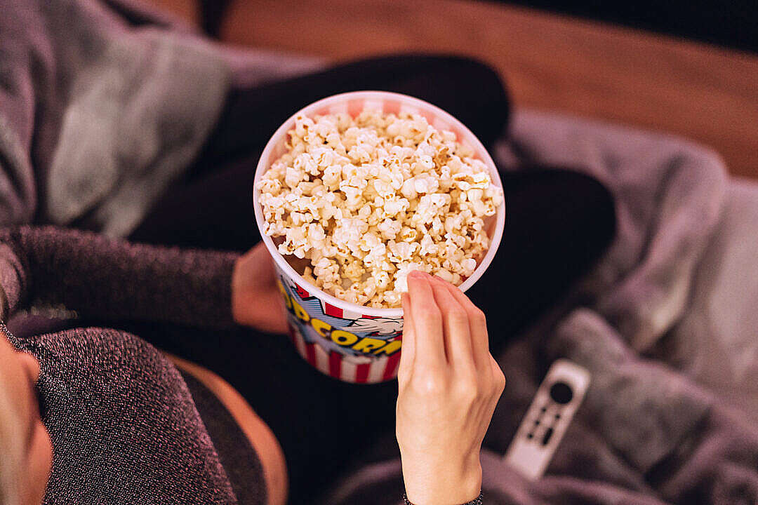 Download Woman Eating Popcorn while Watching TV at Home FREE Stock Photo