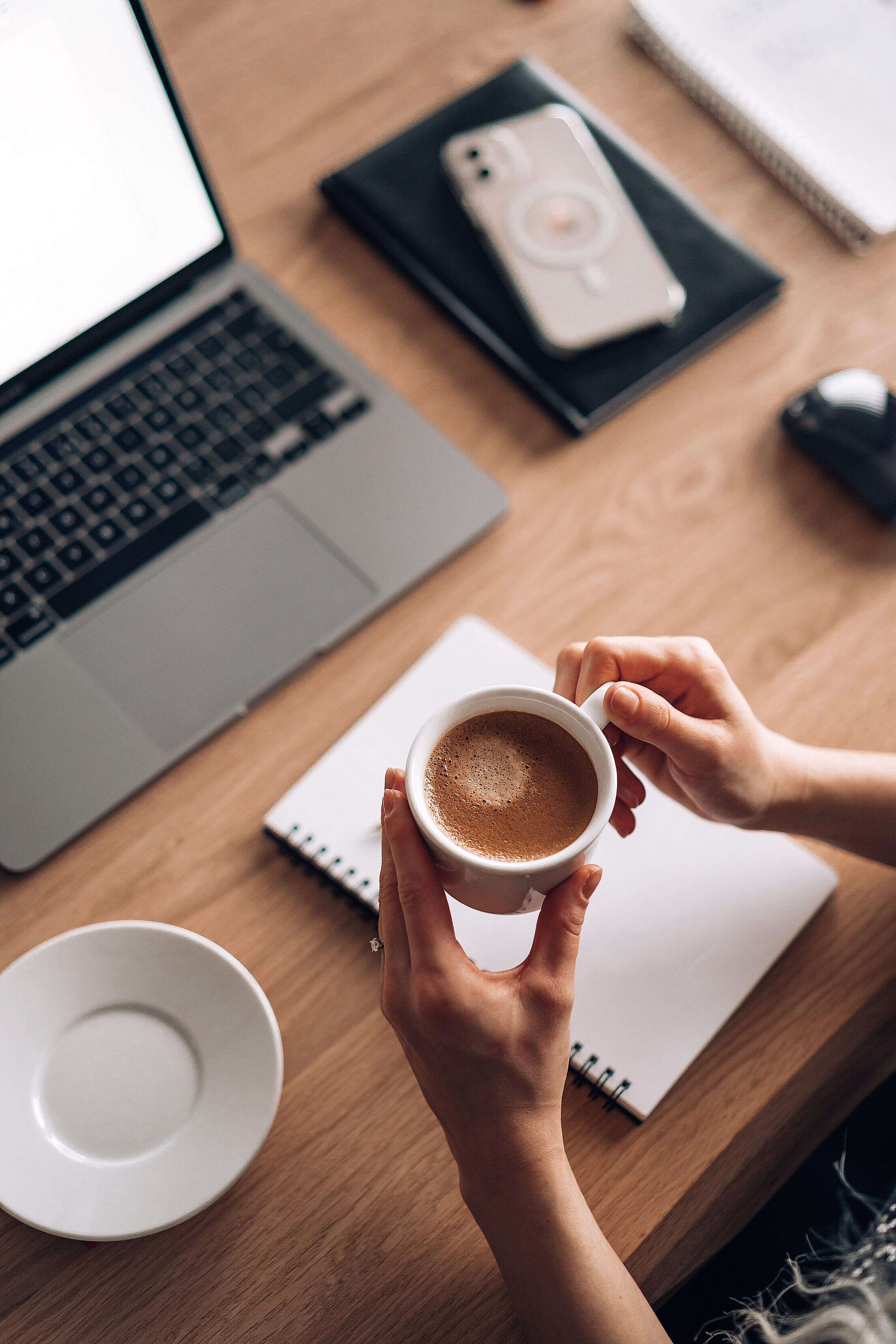 Woman Holding a Cup of Coffee while Writing and Working Free Stock Photo