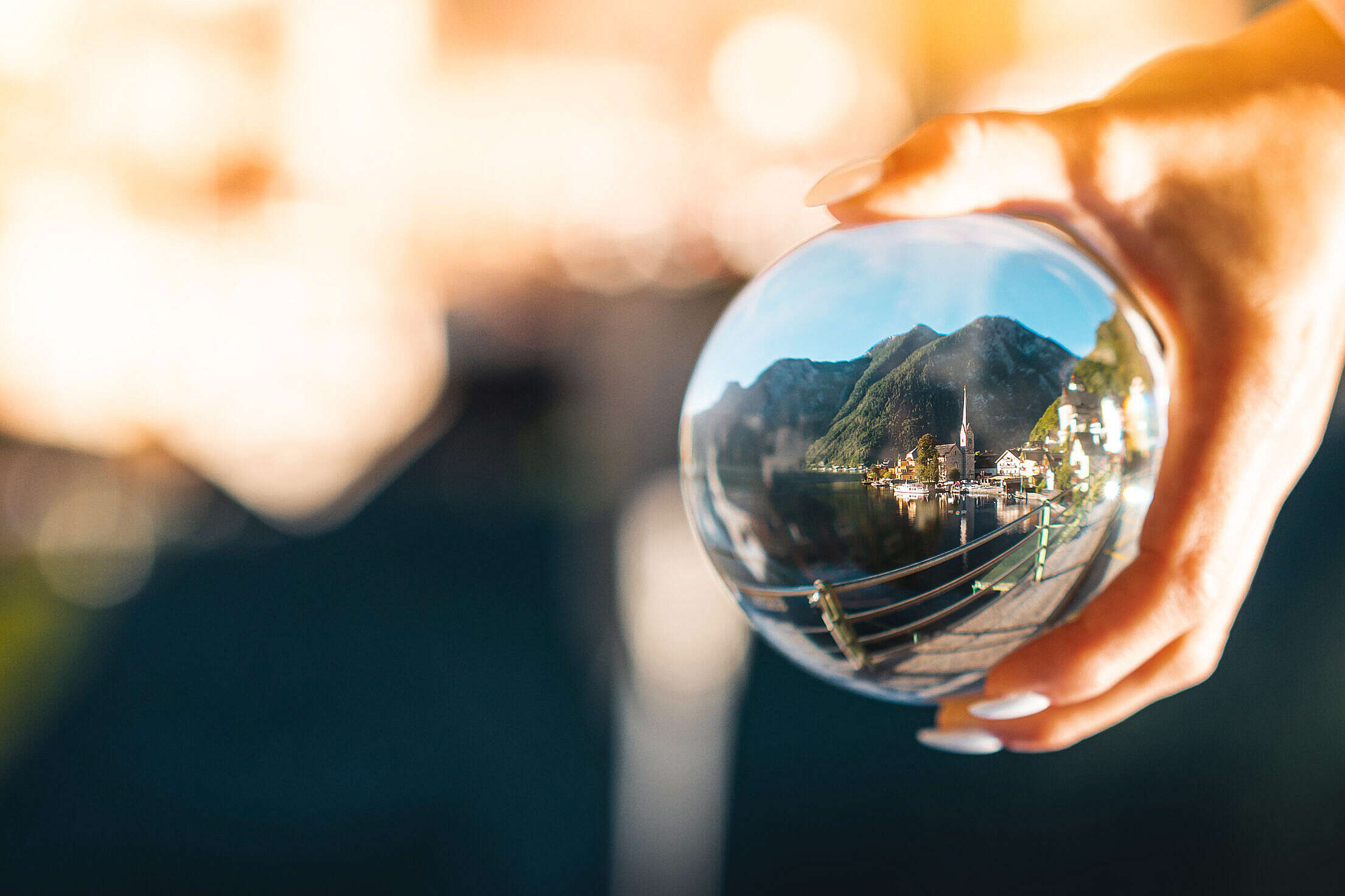 Woman Holding a Glass Ball with Reflection of Hallstatt Village Free Stock Photo