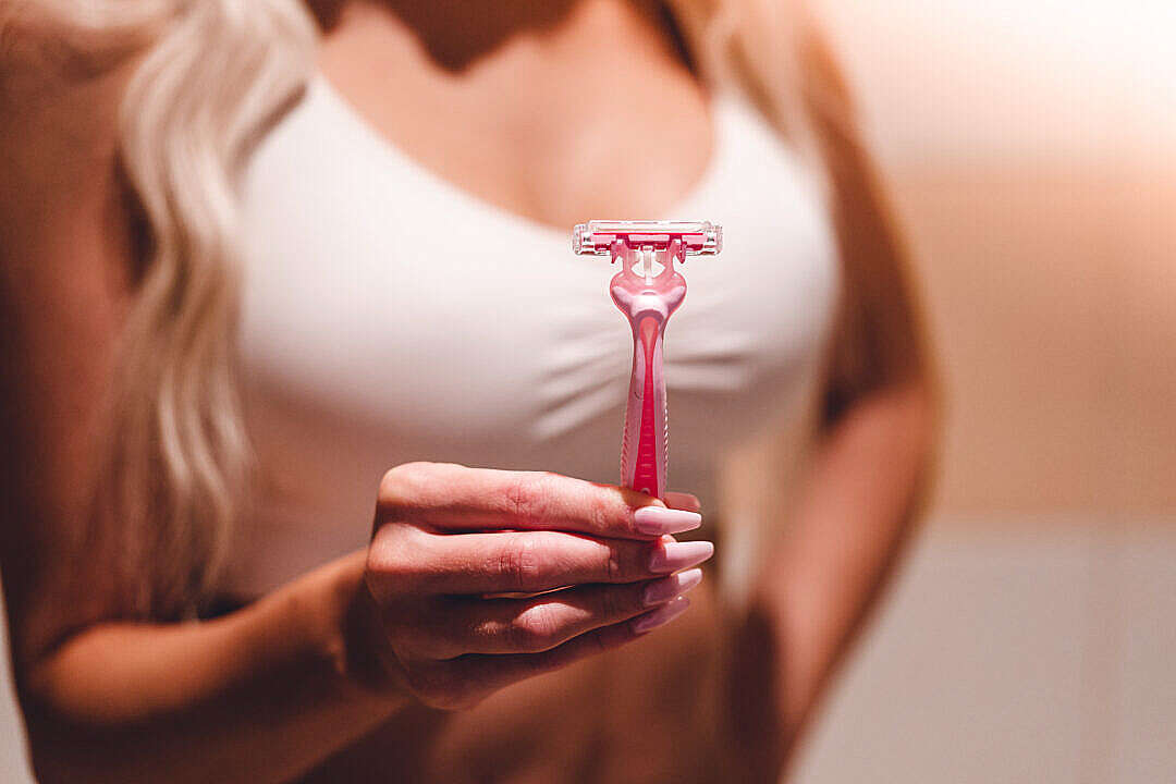 Download Woman Holding a Pink Shaving Razor in Her Hand FREE Stock Photo
