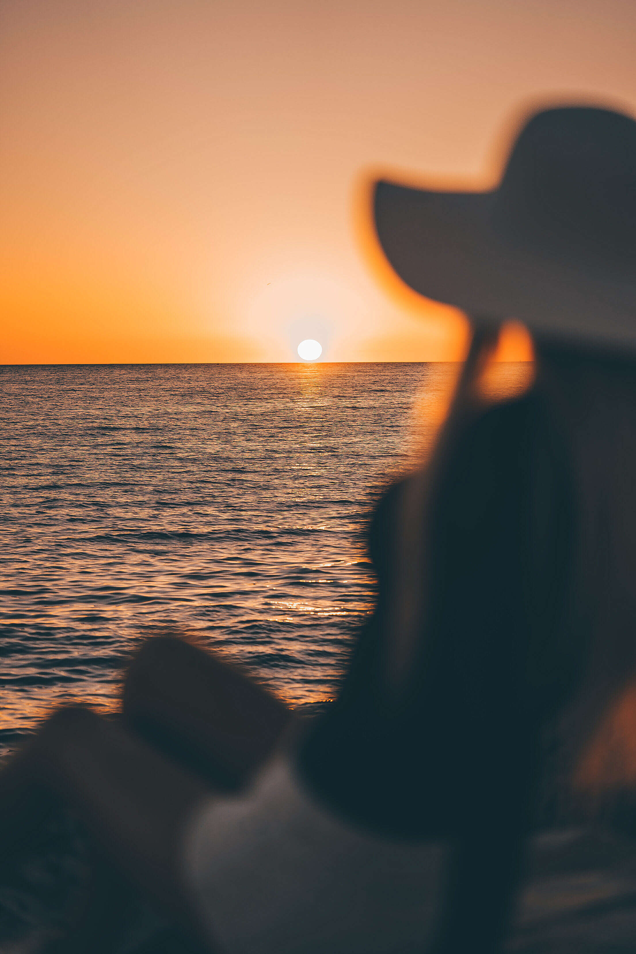 Woman in a Hat Looking at Sunset Above The Sea Free Stock Photo