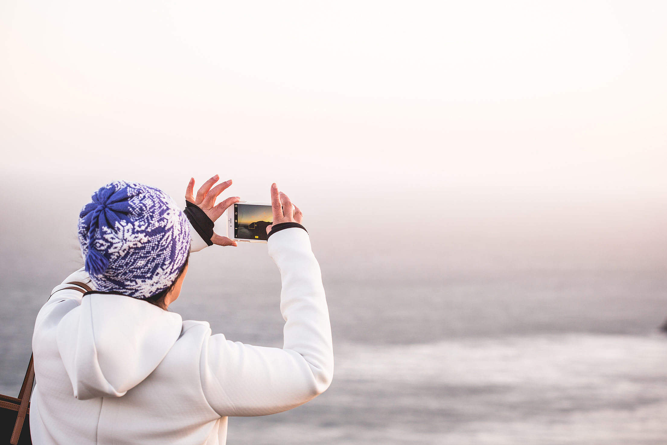 Woman in Winter Hat Taking a Picture of Endless Ocean Free Stock Photo