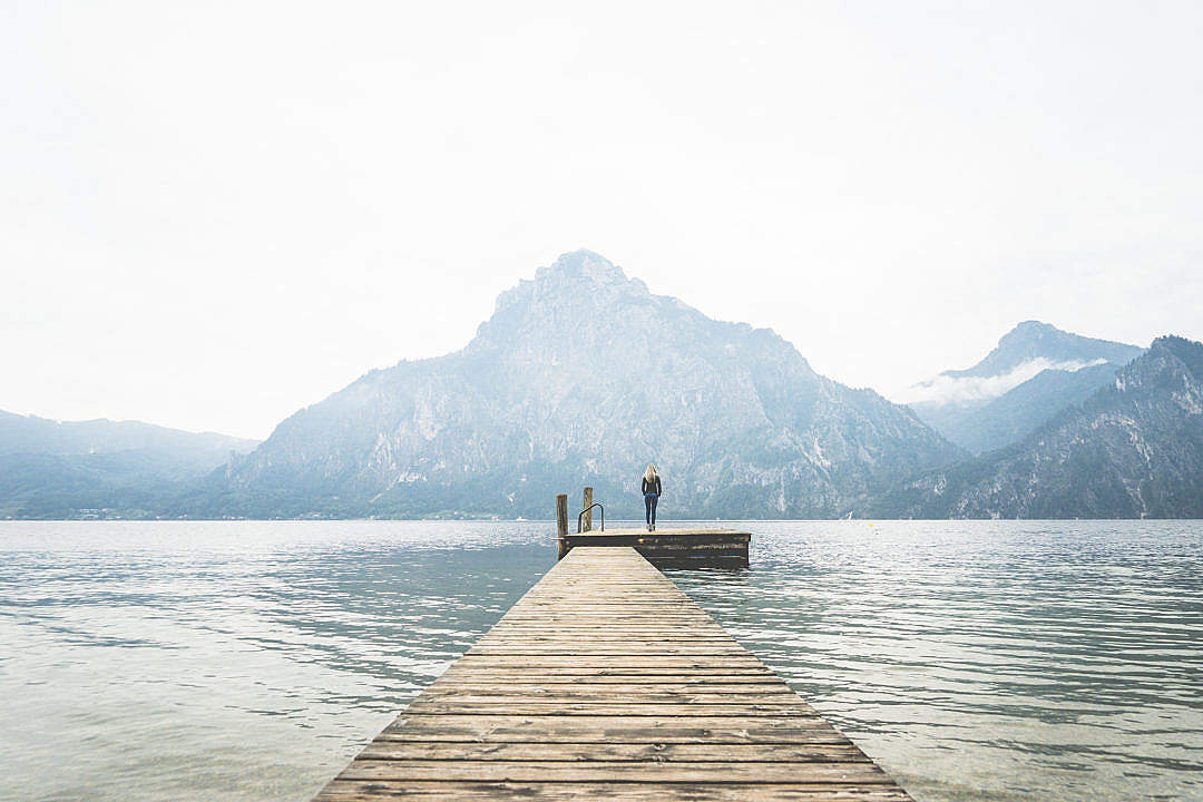 Woman Standing Alone on a Large Wooden Pier on a Lake