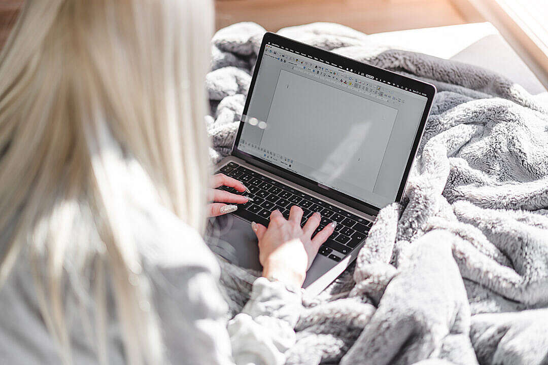 Download Woman Working with Spreadsheet on Laptop in Bed FREE Stock Photo