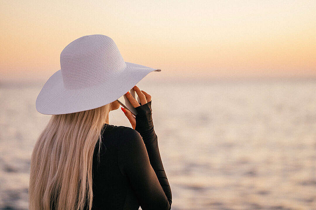 Young Blonde Woman Calling During Sunset by the Sea