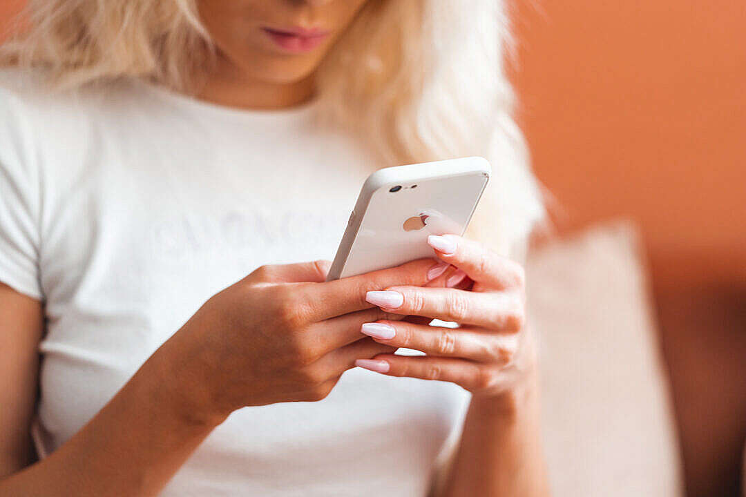 Young Blonde Woman Using White Smartphone