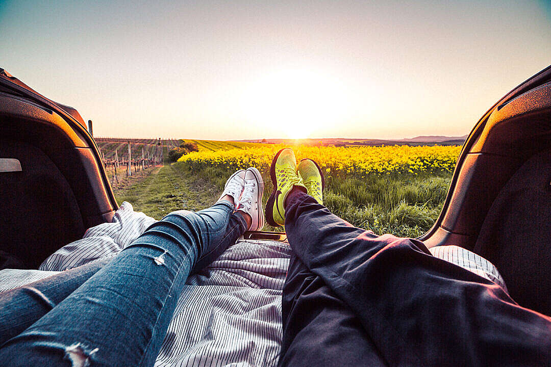 Young Couple Enjoying Romantic Sunset from Car Trunk