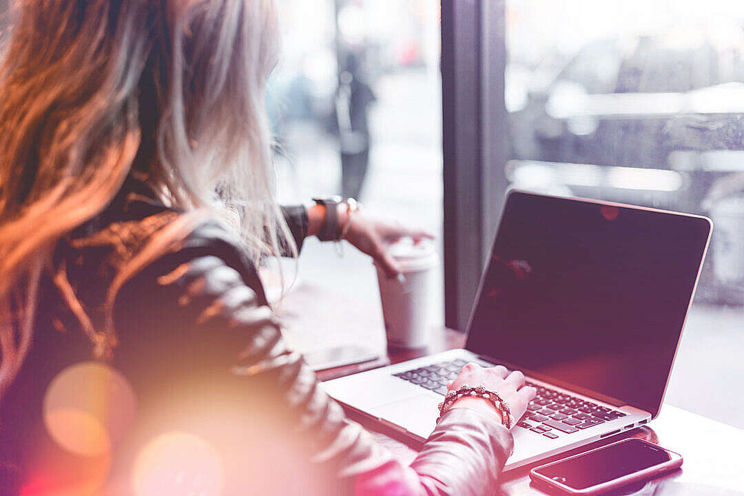 Young Freelance Woman Working Remotely from Café