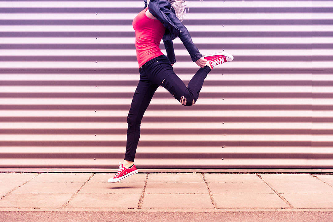 Download Young Happy Woman Jumping in Front of Metal Wall FREE Stock Photo