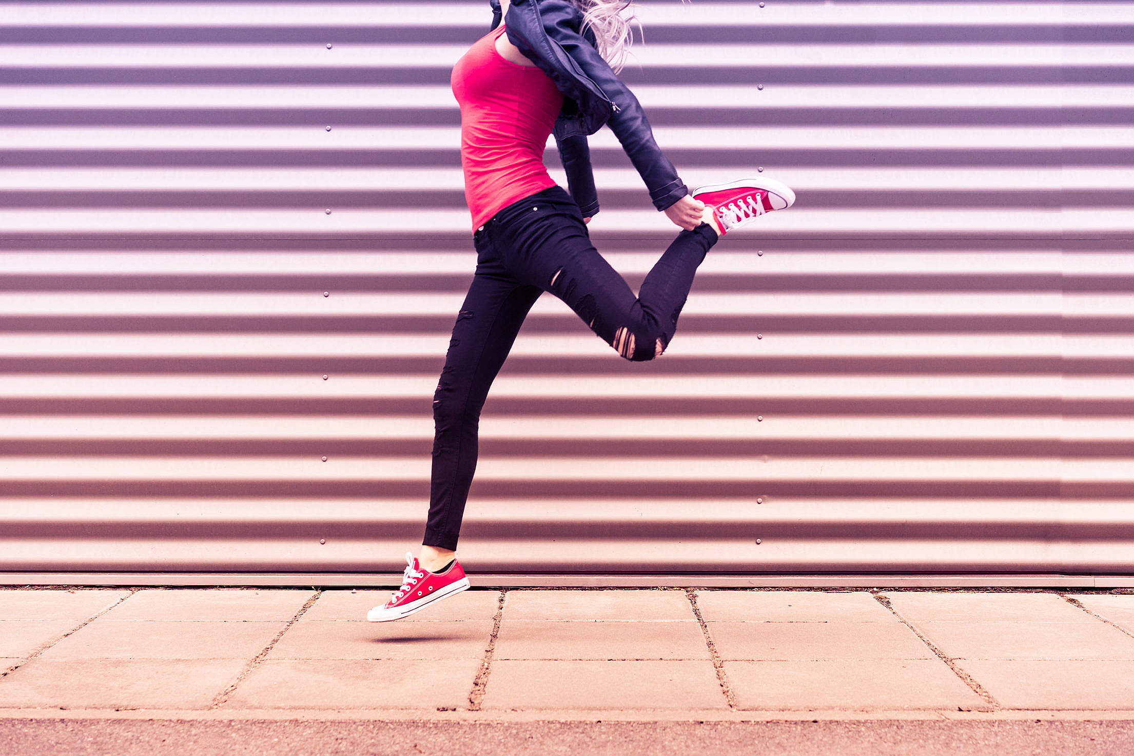 Young Happy Woman Jumping in Front of Metal Wall Free Stock Photo