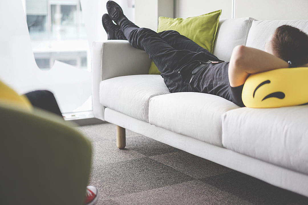 Young Man Napping on White Sofa in the Office