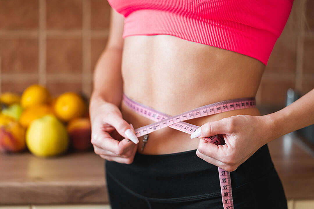 Young Slim Woman Measuring Her Waist by Measure Tape