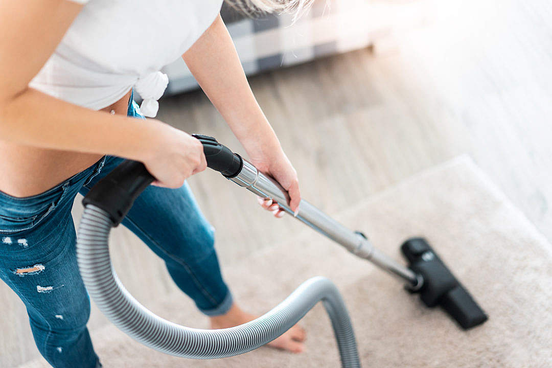 Young Woman Cleaning Carpet with Vacuum Cleaner