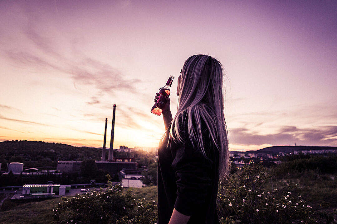 Young Woman Enjoying a Drink in Sunset