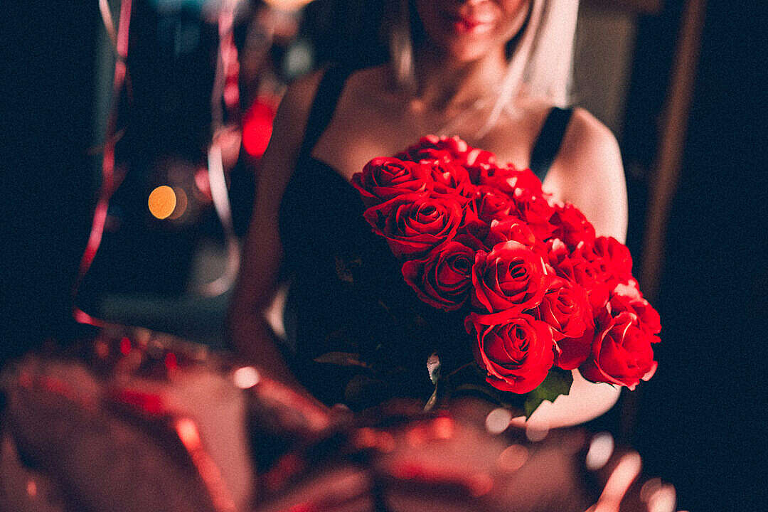 Young Woman Holding a Bouquet of Red Roses on a Date Night