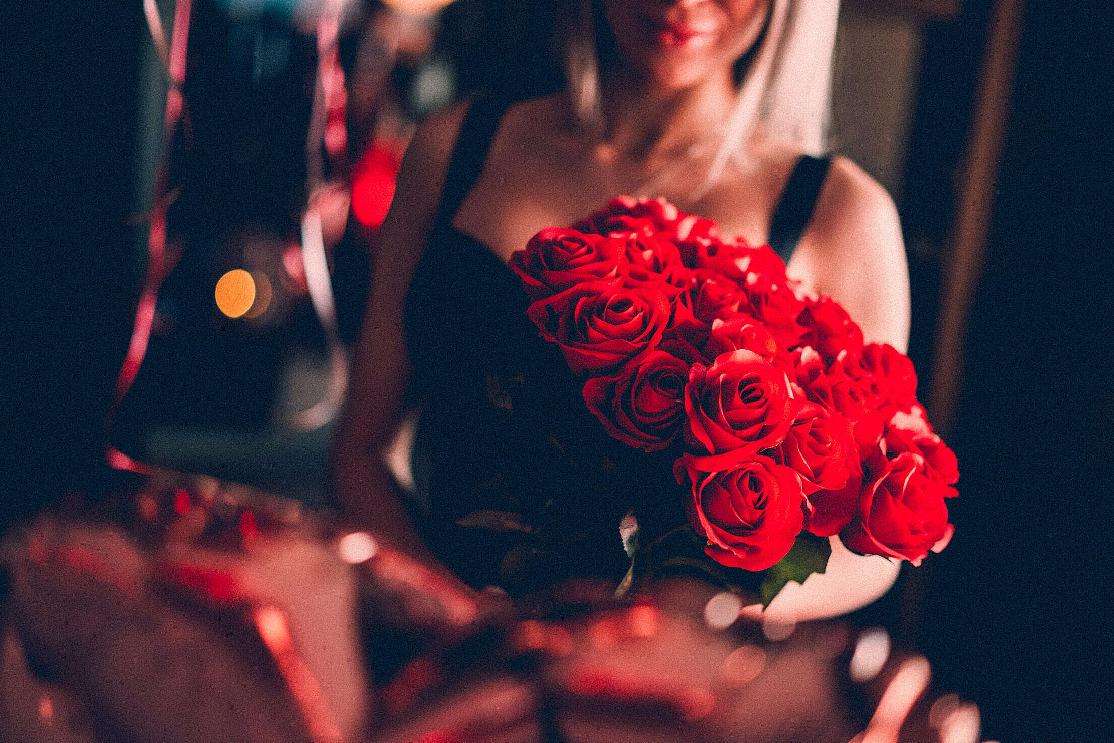 Young Woman Holding a Bouquet of Red Roses on a Date Night Free Stock Photo