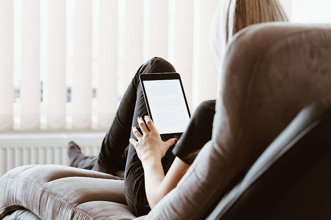 Download Young Woman Reading eBooks on Her iPad Tablet FREE Stock Photo