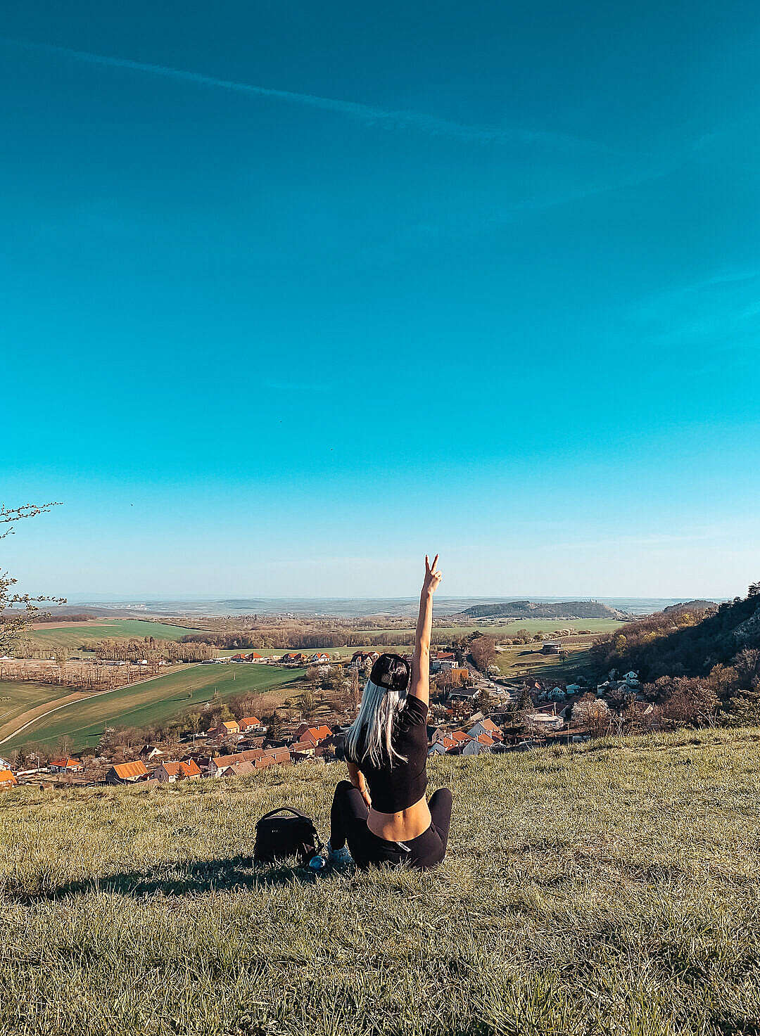 Young Woman Sitting on a Hill Showing Peace Sign