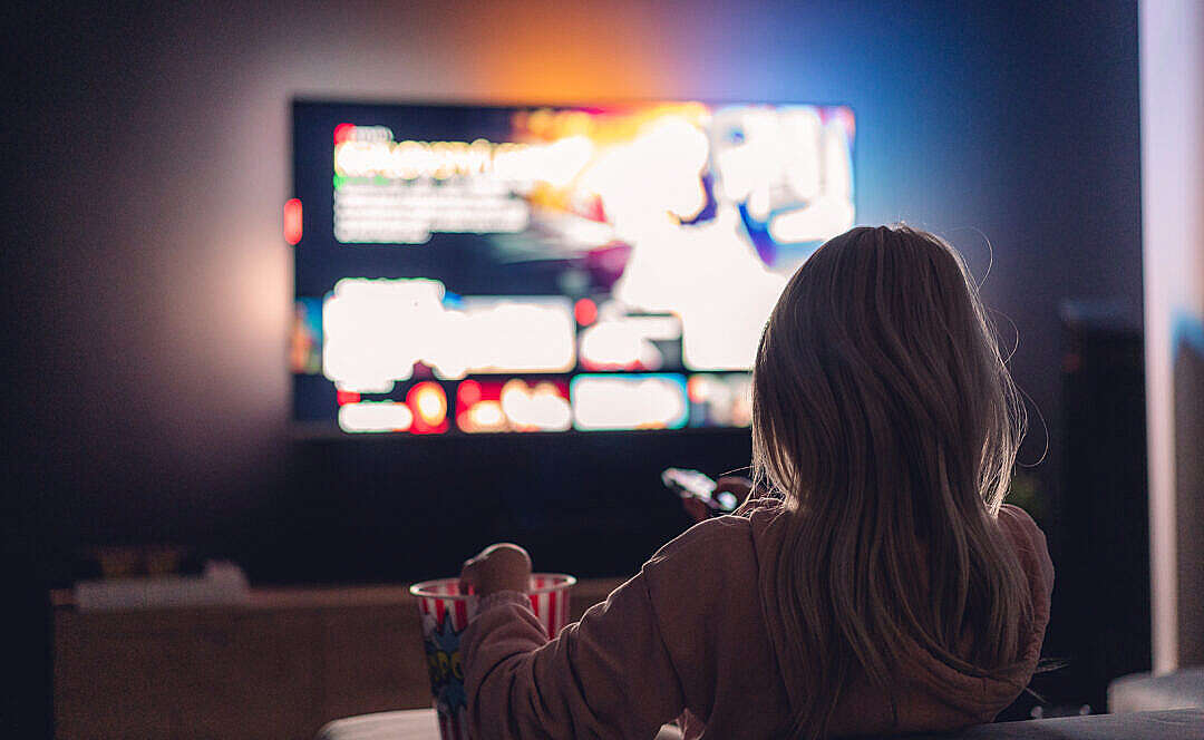 Young Woman Watching TV and Eating Popcorn at Night
